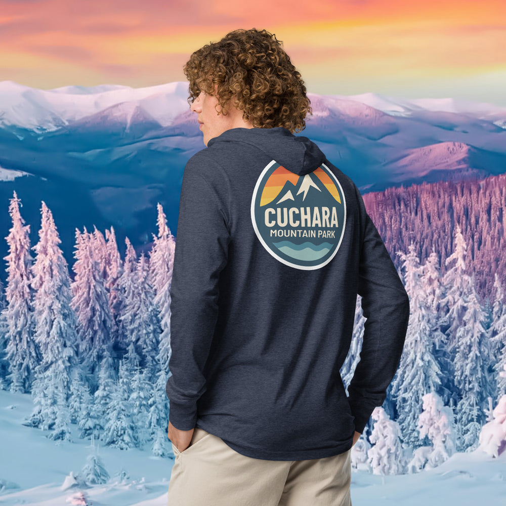 Person wearing a black hoodie with 'Cuchara Mountain Park' logo in a snowy mountain landscape. Person wearing a black hoodie with a logo against a snowy mountain landscape. lightweight long-sleeve hooded tee, unrestricted movement shirt, all-season layering top, comfortable athletic fit, stylish outdoor outfit, year-round trail essential, men's hooded t-shirt, cuchara mountain park hoodie, cuchara mountain park long sleeve shirt