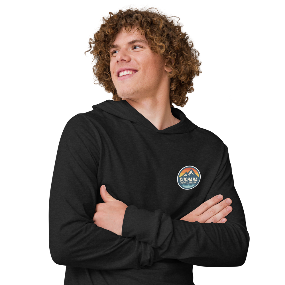 Person wearing a black hoodie with 'Cuchara Mountain Park' logo in a snowy mountain landscape. Person wearing a black hoodie with a logo against a snowy mountain landscape. lightweight long-sleeve hooded tee, unrestricted movement shirt, all-season layering top, comfortable athletic fit, stylish outdoor outfit, year-round trail essential, men's hooded t-shirt, cuchara mountain park hoodie, cuchara mountain park long sleeve shirt