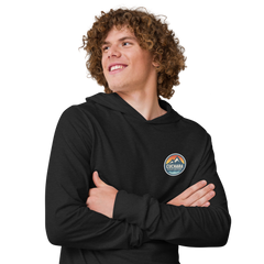 Person wearing a black hoodie with 'Cuchara Mountain Park' logo in a snowy mountain landscape. Person wearing a black hoodie with a logo against a snowy mountain landscape. lightweight long-sleeve hooded tee, unrestricted movement shirt, all-season layering top, comfortable athletic fit, stylish outdoor outfit, year-round trail essential, men's hooded t-shirt, cuchara mountain park hoodie, cuchara mountain park long sleeve shirt