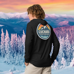 Person wearing a black hoodie with 'Cuchara Mountain Park' logo in a snowy mountain landscape.  Person wearing a black hoodie with a logo against a snowy mountain landscape.  lightweight long-sleeve hooded tee, unrestricted movement shirt, all-season layering top, comfortable athletic fit, stylish outdoor outfit, year-round trail essential, men's hooded t-shirt, cuchara mountain park hoodie, cuchara mountain park long sleeve shirt