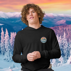 Person wearing a black hoodie with 'Cuchara Mountain Park' logo in a snowy mountain landscape.  Person wearing a black hoodie with a logo against a snowy mountain landscape.  lightweight long-sleeve hooded tee, unrestricted movement shirt, all-season layering top, comfortable athletic fit, stylish outdoor outfit, year-round trail essential, men's hooded t-shirt, cuchara mountain park hoodie, cuchara mountain park long sleeve shirt