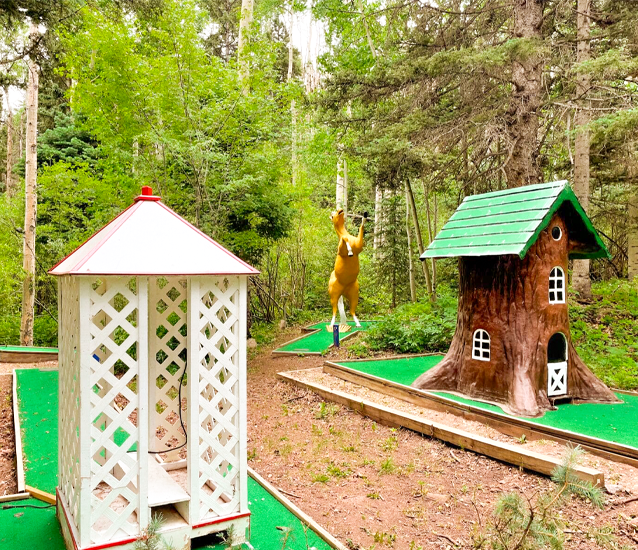 Family playing a round of free mini-golf at Cuchara Mountain Park, with putters and balls from the Cuchara Mountain Mercantile, offering affordable summer fun.  Cuchara Mountain Park mini golf, free miniature golf Colorado, affordable family fun Cuchara, Cuchara Mountain Mercantile putt putt, casual outdoor mini-golf course, family friendly fun Huerfano County, self-paced mini golf Colorado, Cuchara summer activities