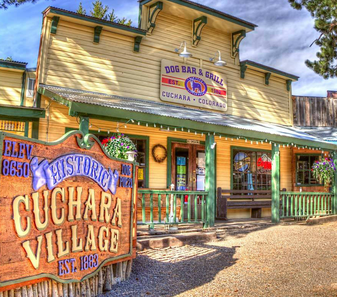 Wooden building with 'Dog Bar & Grill' sign and 'Historic Cuchara Village' sign in front.  Cuchara villiage, historic cuchara village, dog bar and grill