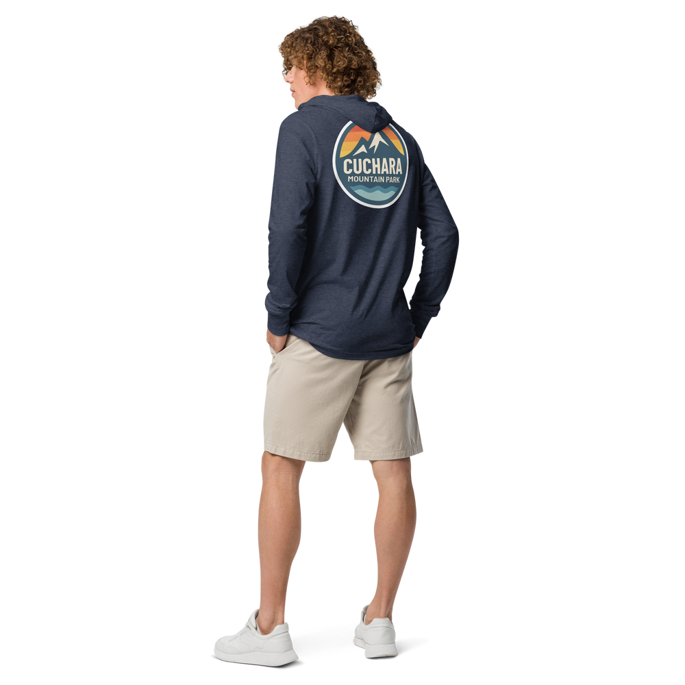 Person wearing a black hoodie with 'Cuchara Mountain Park' logo in a snowy mountain landscape.  Person wearing a black hoodie with a logo against a snowy mountain landscape.  lightweight long-sleeve hooded tee, unrestricted movement shirt, all-season layering top, comfortable athletic fit, stylish outdoor outfit, year-round trail essential, men's hooded t-shirt, cuchara mountain park hoodie, cuchara mountain park long sleeve shirt